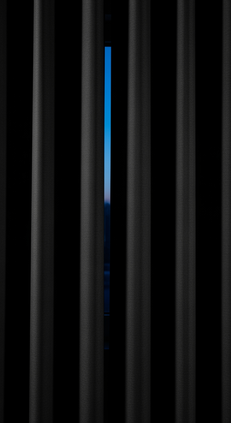 A close view of a heavy blackout curtain in a dark nursery, with a sliver of twilight showing at the edge.