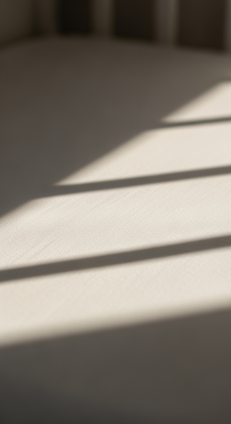 A macro close-up of the texture of a clean white crib sheet, with soft light creating gentle shadows, symbolizing peaceful rest.